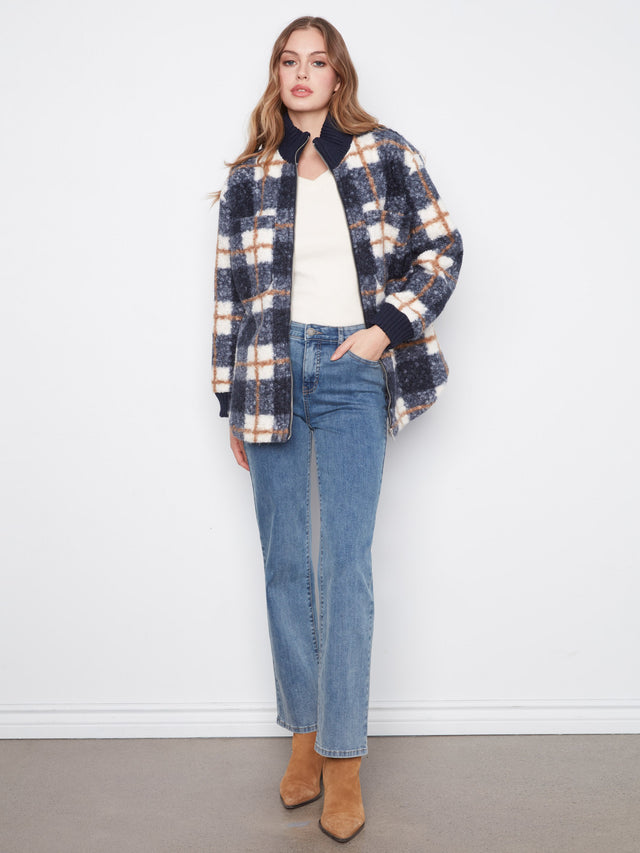 A woman styles a plaid jacket outfit with straight-leg jeans and tan ankle boots