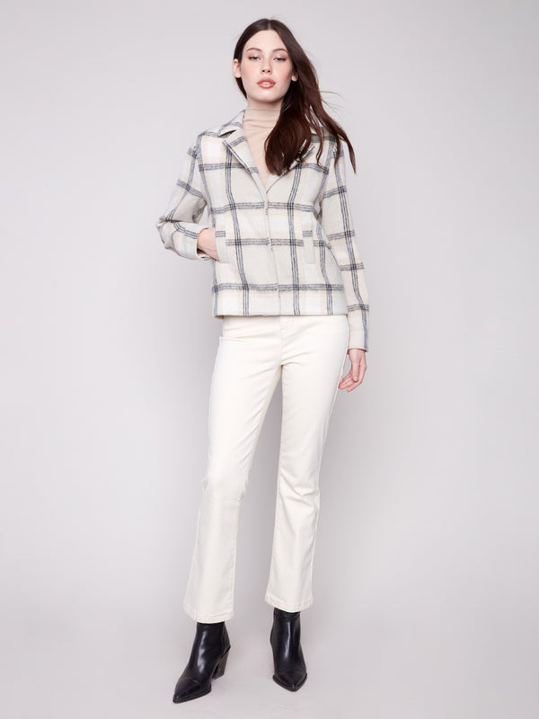 Stylish beige plaid coat with functional welt pockets and classic design elements. Perfect for any occasion by Charlie B.