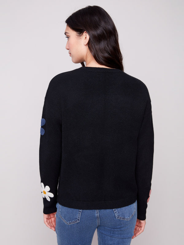 Long-sleeved black sweater highlighted by colorful boucle flowers for a chic touch to any outfit by Charlie B.