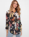 Floral print blouse featuring a classic shirt collar and button-front closure, perfect for versatile styling by Charlie B.