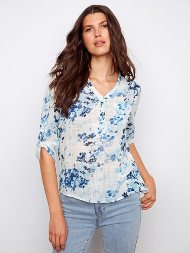 Stylish blouse with a convenient chest pocket, adding functionality to its beautiful blue floral design. By Charlie B.