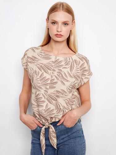 Elegant printed top in beige, designed with a classic boat neckline and charming tie at the hem by Charlie B.