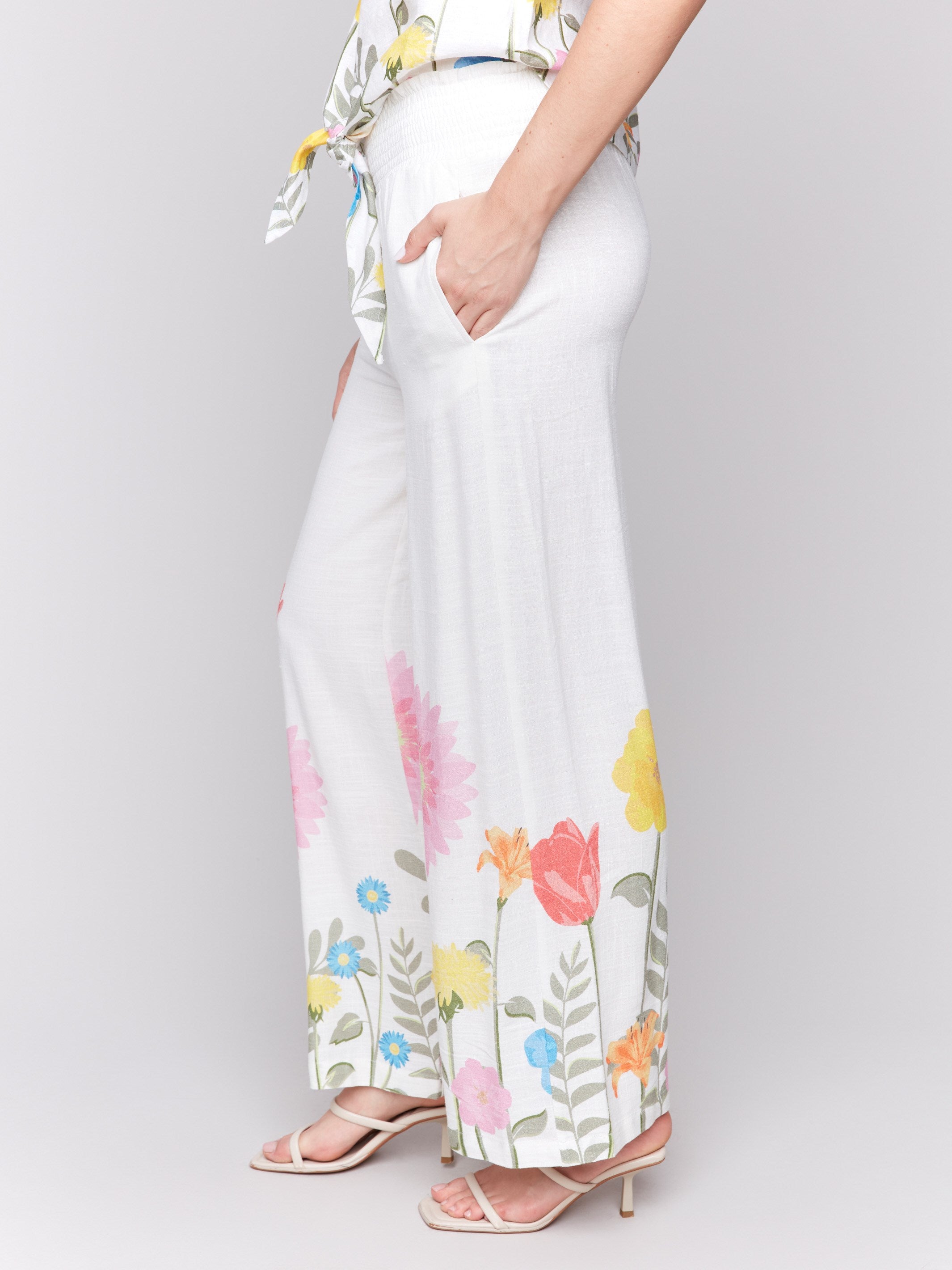Chic white pants featuring convenient side pockets and vibrant floral accents by Charlie B.