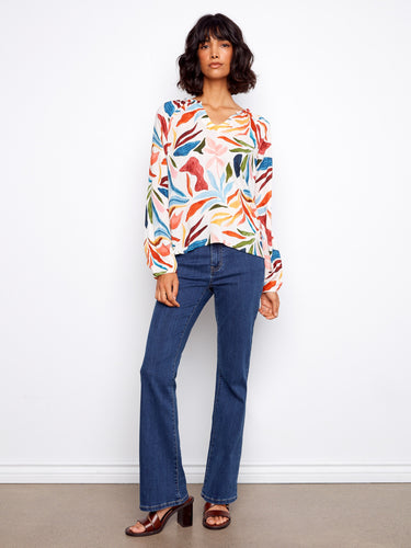 This stylish blouse showcases raglan sleeves with a lively multicolor print, adding a touch of elegance. By Charlie B.