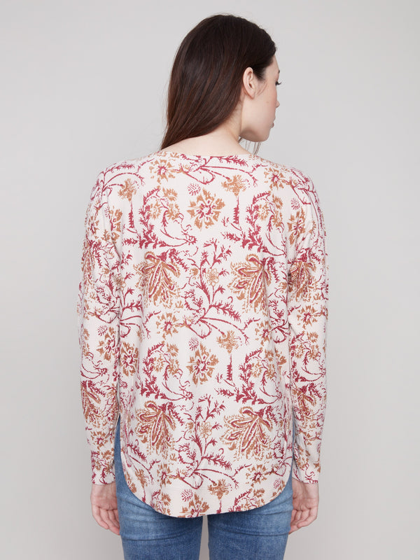 Abstract floral print sweater with rounded hem, highlighting ribbed sleeves and elegant side pockets by Charlie B.