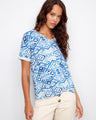 Blue patterned top with a stylish V-neckline, paired elegantly with beige pants. Perfect for casual outings by Charlie B.