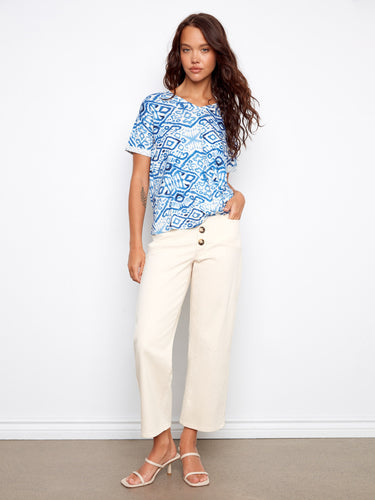 Chic blue top featuring a unique side knot detail, styled effortlessly with cream trousers and sandals by Charlie B.