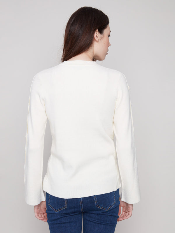 Elegant ecru sweater showcasing ribbed texture and button accents by Charlie B.