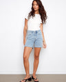 Denim shorts featuring a regular rise and comfortable stretch, paired with a simple white tee for casual style by Charlie B.