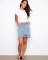 Denim skirt featuring short length and front buttons, styled casually with a white top for a chic look by Charlie B.