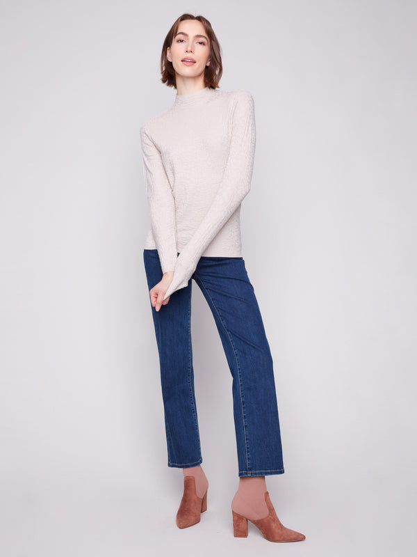 Refined oat long-sleeve sweater in textured fabric, styled beautifully with fashionable blue jeans by Charlie B.