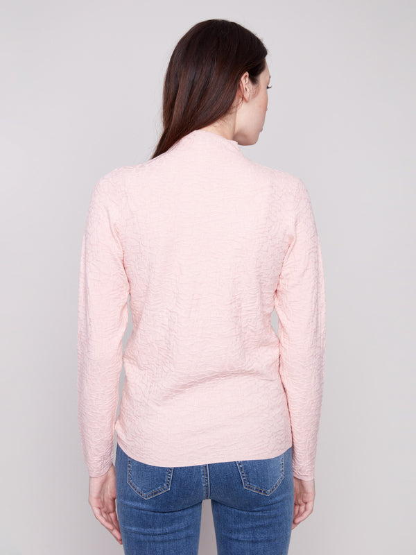 Elegant ballet pink long-sleeve sweater showcasing textured fabric and slim silhouette, styled with jeans by Charlie B.