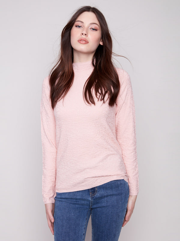 Chic ballet pink mock neck sweater crafted from textured fabric, teamed elegantly with blue denim by Charlie B.