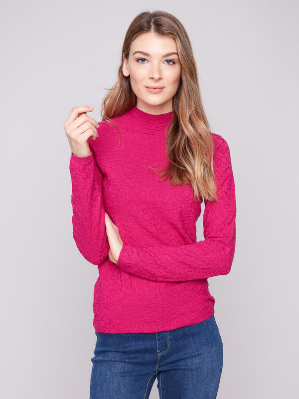 Textured hibiscus sweater styled elegantly with denim, showcasing its mock neck design by Charlie B.