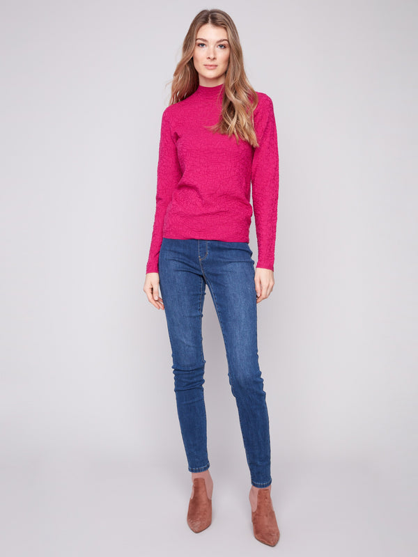 Mock neck and textured details define this chic hibiscus sweater styled with denim by Charlie B.