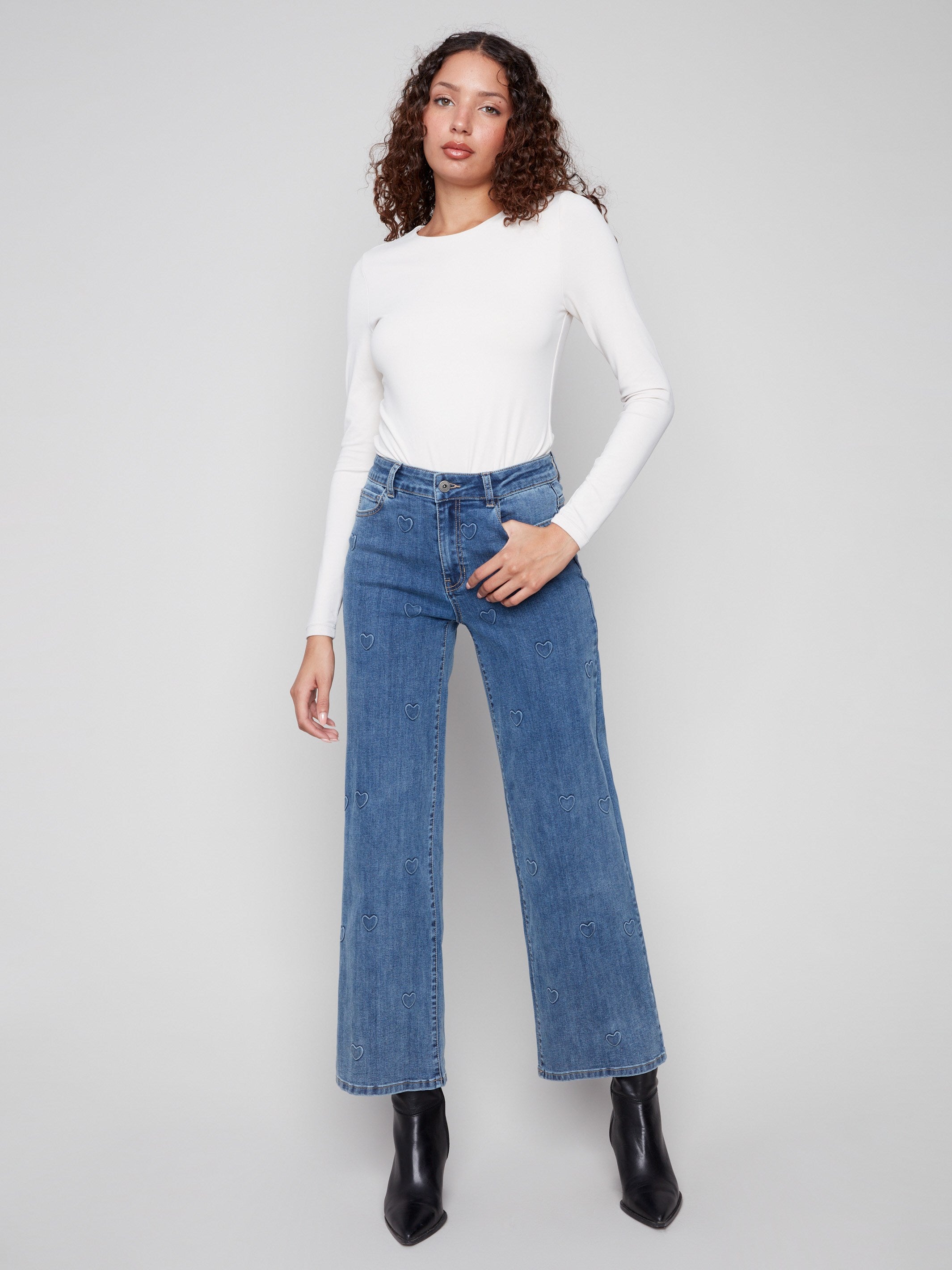 These blue jeans feature a long length and embossed heart pattern, offering a chic style by Charlie B.